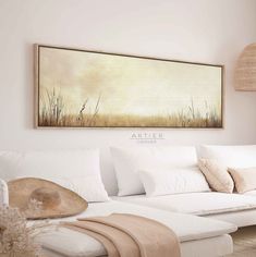 a living room with white furniture and a large painting on the wall over the couch