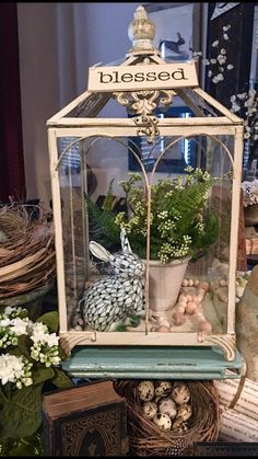 a white birdcage filled with flowers and eggs sitting on top of a table