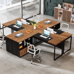 an office desk with two laptops on it and a plant in the middle, surrounded by chairs