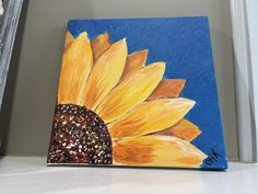 a painting of a yellow sunflower on a blue background