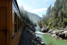 a train traveling down tracks next to a river