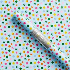 a tube of lip bale sitting on top of a colorful polka dot print table cloth