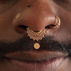 a close up of a man's nose with gold jewelry on top of it