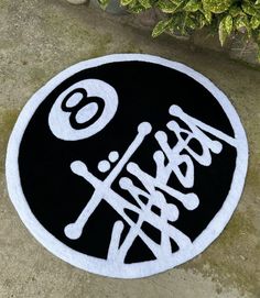 a black and white round rug with the number 60 on it, in front of some plants