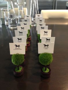 there are many place cards on top of the small grass planters in front of each other