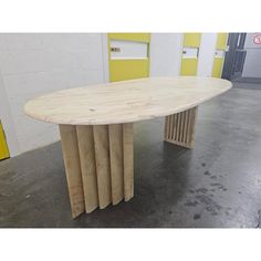 a table made out of wooden sticks in a room with yellow doors and concrete flooring