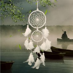 there is a white dream catcher hanging from the tree in front of two canoes