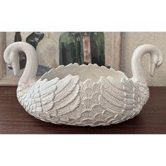 a white swan shaped bowl sitting on top of a wooden table