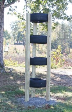 a tire rack made out of old tires in the grass next to a large tree