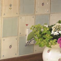 a vase filled with flowers sitting on top of a counter next to a wall covered in tiles