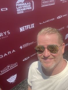 a man wearing sunglasses standing in front of a red wall with the words netflix on it