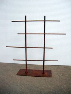 a sculpture made out of wooden sticks on top of a cement floor next to a white wall