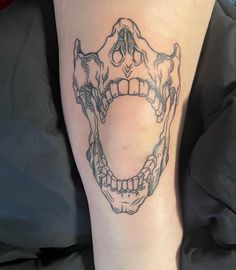 a person with a tattoo on their leg that has a skull in the shape of a mouth