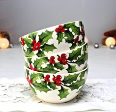 three christmas holly and berry decorated bowls on a doily with candles in the background