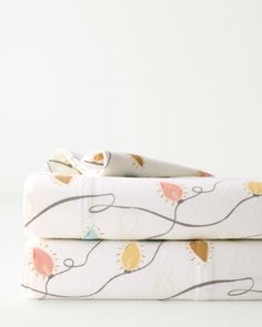 two folded sheets are sitting next to each other on a white surface with an orange, yellow and blue design