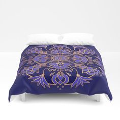 a blue and gold comforter cover with an intricate design on the front, along with two pillows