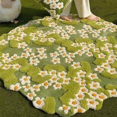 a woman sitting on the ground next to a rug with flowers and leaves in it