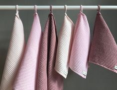 four pink and white towels hanging on a rack