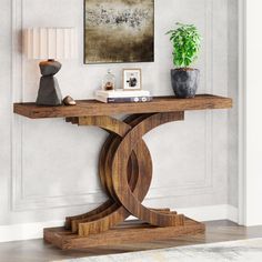 a wooden table sitting in front of a painting on the wall next to a potted plant