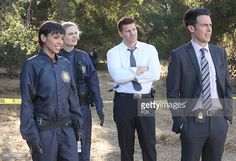 three men in suits and ties standing next to each other on a dirt road with trees in the background