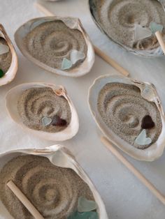 several oysters with sea glass in them on a white tablecloth and wooden sticks