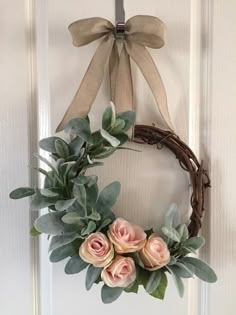 a wreath with pink roses and eucalyptus leaves hangs on the front door's wall