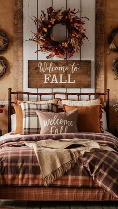 a bed with plaid comforter and pillows in front of a welcome to fall sign