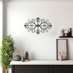 a wall mounted clock on the side of a white wall next to a potted plant