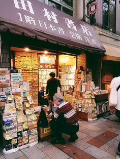 two men are looking at books in front of a store