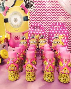 a table topped with lots of yellow and pink candy jars filled with minion candies