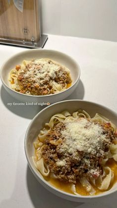 two bowls of pasta with meat sauce and parmesan cheese on the top one is empty