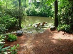 there are two chairs that are sitting on the side of the river in the woods