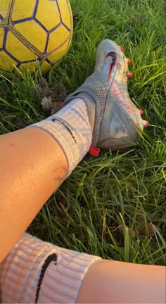 a person's legs with socks and soccer balls in the grass