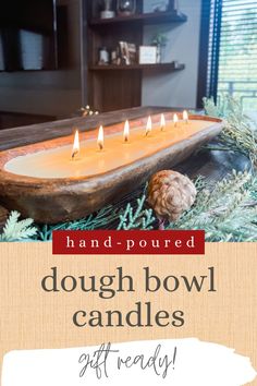 a wooden bowl filled with candles sitting on top of a table next to pine cones