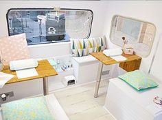 the inside of a small room with two desks and pillows on top of it