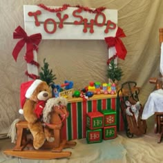 a teddy bear sitting on a rocking horse in front of a toy shop sign and christmas decorations