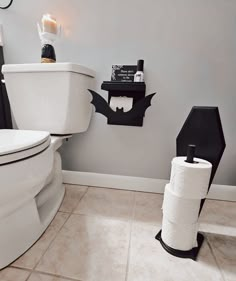 a bathroom with two toilet paper dispensers on the wall, and a batman themed roll holder