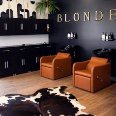 Two caramel-colored shampoo systems stand in front of a black accent wall with salon’s logo “Blonde.” Accent Wall For Salon Suite, Salon Processing Area, Shampoo Room Ideas Salon, Shampoo Station Ideas, Shampoo Bowl Ideas Salon, Salon Backbar Ideas, Small Salon Decor, Luxury Salon Interior Design, Salon Shampoo Bowl