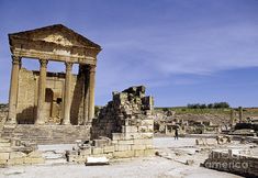 the ruins of an ancient city are shown in this photo, with people walking around them