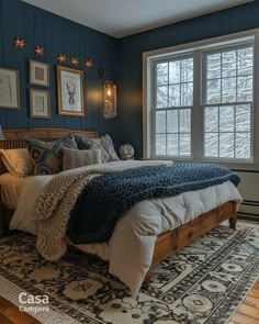 a bedroom with blue walls and white bedding in front of a large window that has framed pictures on the wall