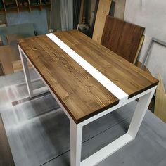 a table made out of wood and white metal with chairs behind it in a shop