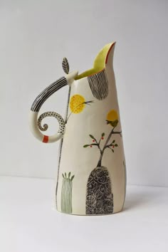 a ceramic pitcher with an artistic design on it's side and the handle is bent down