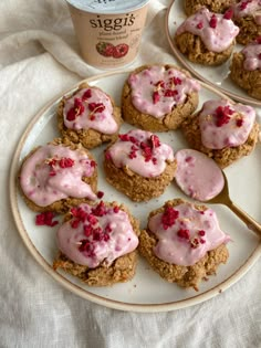 there are some cupcakes with pink icing on the plate