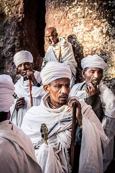 several men in turbans standing next to each other and one is holding a stick