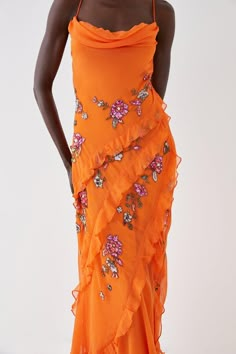 a woman in an orange dress with flowers on it