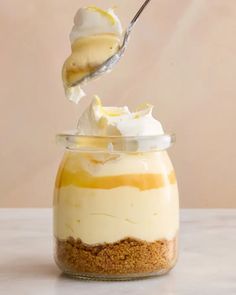 a spoonful of lemon cheesecake in a glass jar with whipped cream on top