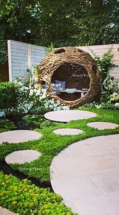 an outdoor garden with stepping stones, grass and a circular wicker bed in the middle