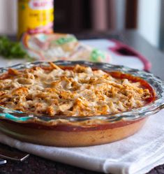 a casserole dish with meat and cheese in it sitting on a table next to a bottle of mustard