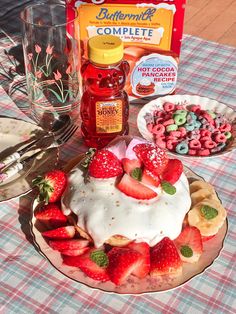 a cake with strawberries, bananas and other food items on it sitting on a table