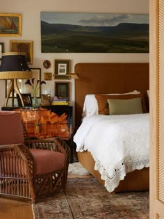 a bed room with a neatly made bed next to a chair and pictures on the wall